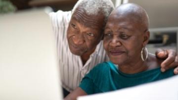 A senior couple look at a computer.